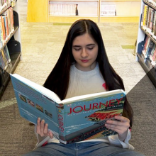 Teen girl sitting on the floor reading a book