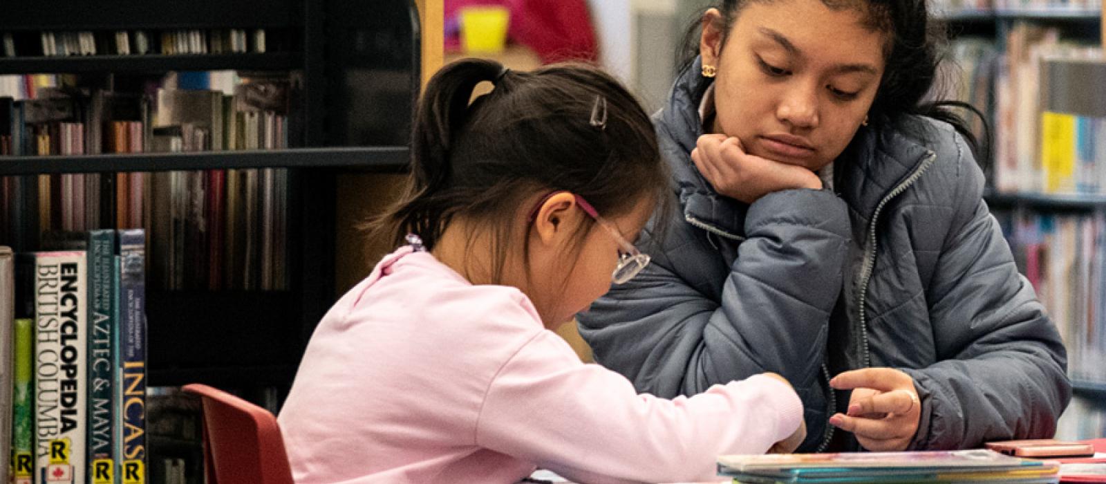 Teenager helping a child with their reading