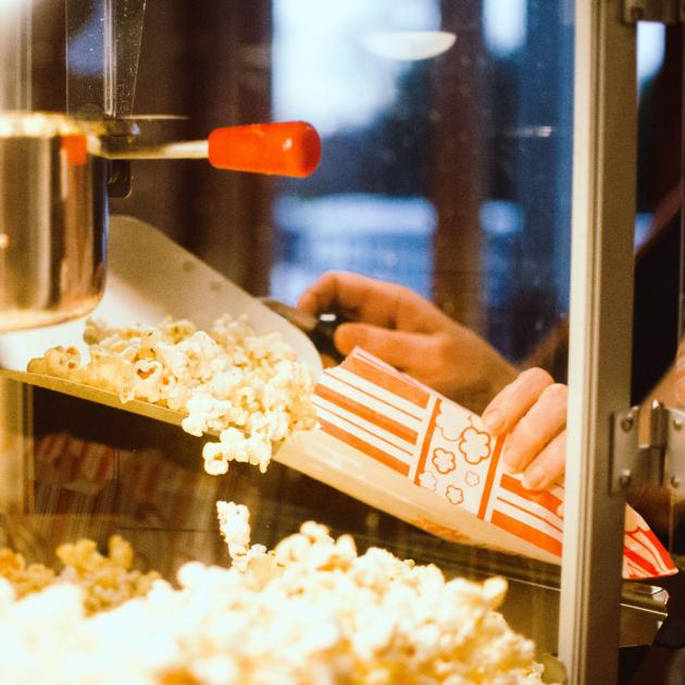 Photograph of a person getting popcorn out of a popcorn maker at night