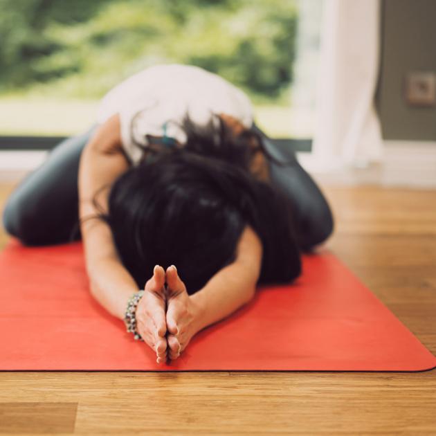 Woman doing yoga on orange mat and wood floor