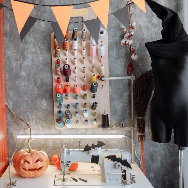 A photograph of a sewing machine with spools of thread, pumpkins and a dress form