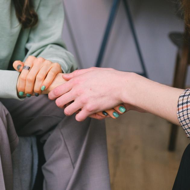 Two people sitting across from each other holding hands