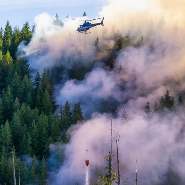 Helicopter dragging water sling over forest fire