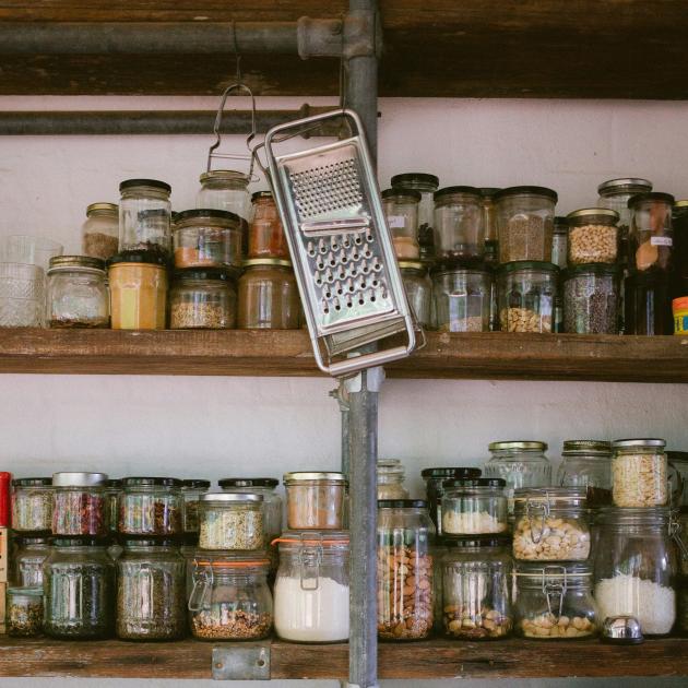 Two shelves of jars full of spices and dried food