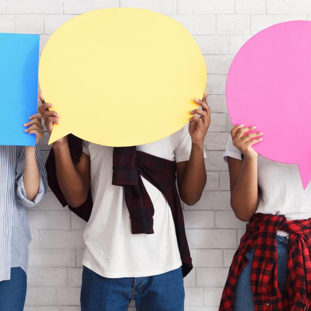 Three youth hold up speech bubble signs covering their faces