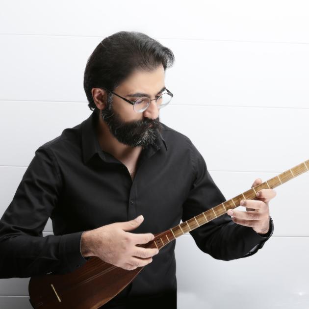 A bearded man holding a musical instrument. 