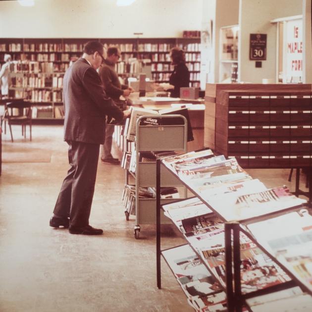 A man browsing a book cart in NVCL circa 1970