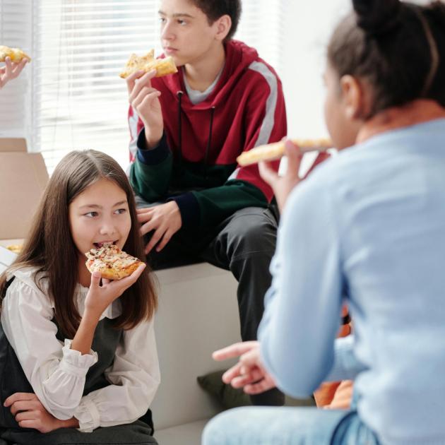 3 teens eating pizza