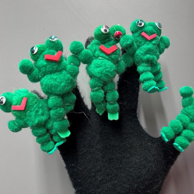 Black glove with 5 green frogs attached to each finger