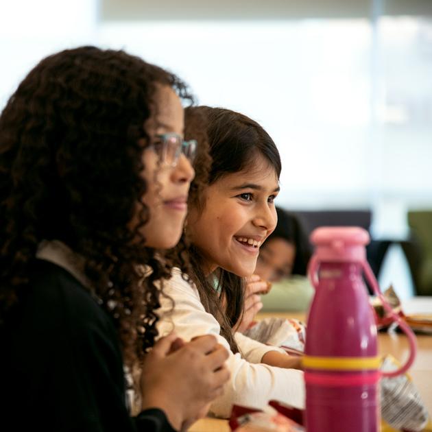 A photograph of two tweens looking to the right and smiling