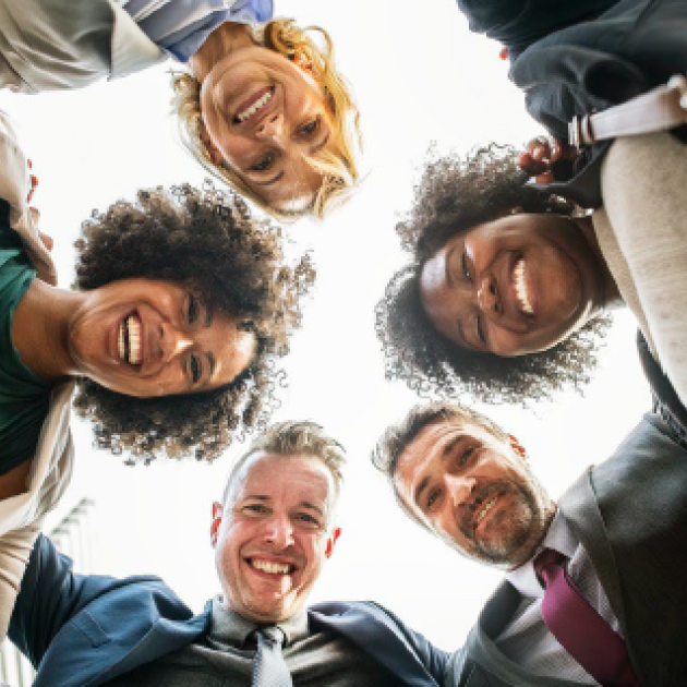 A group of men and women circling and smiling at a camera 