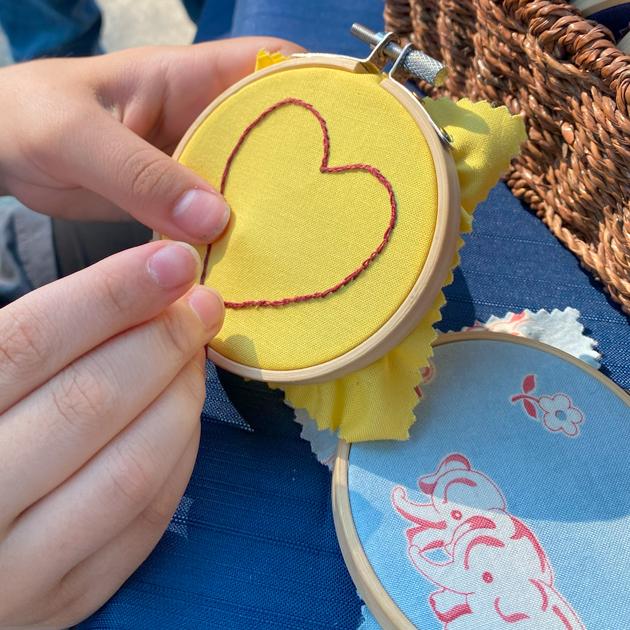 A photograph of a red embroidered heart on a yellow background.