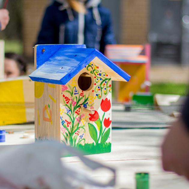 hand-painted wooden birdhouse with a blue roof