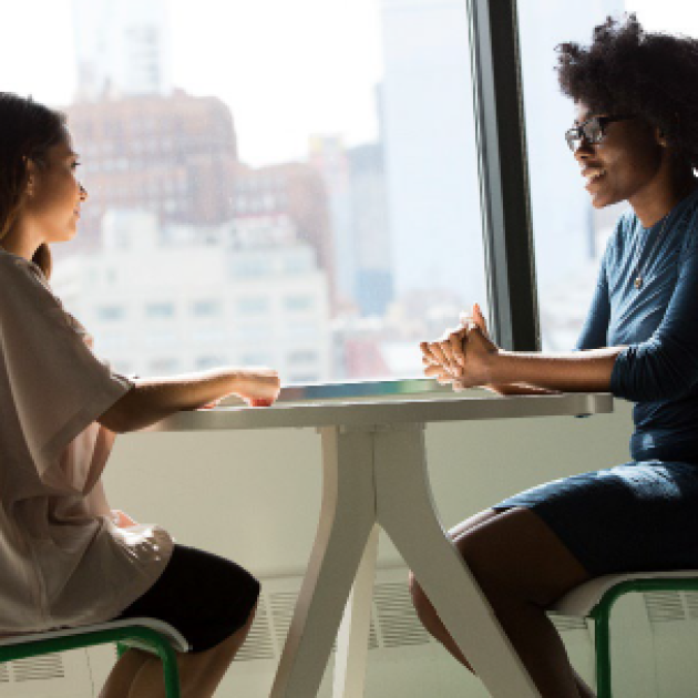 Two people sitting around a table and talking 